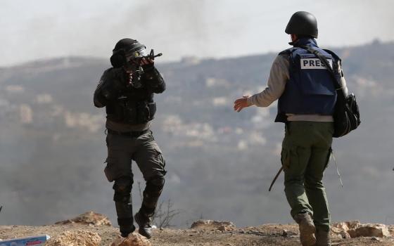 جندي إسرائيلي يصوب سلاحه نحو صحفي
