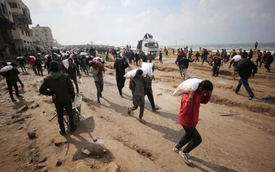 أهالي غزة يحملون أكياس الطحين بعد أن تم إدخاله من بعد فترة طويلة