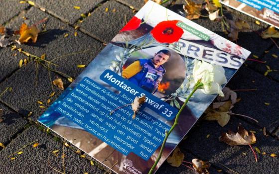 ورقة تحمل صورة صحفي استشهد في غزة