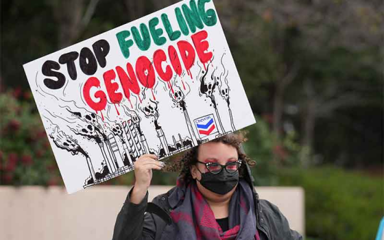 متضامنة ترفع لافتة تدعو لإنهاء إبادة غزة