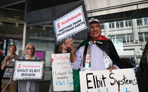 محتج يرفع لافتات إدانة لبنك سكوتيا الداعم للاحتلال