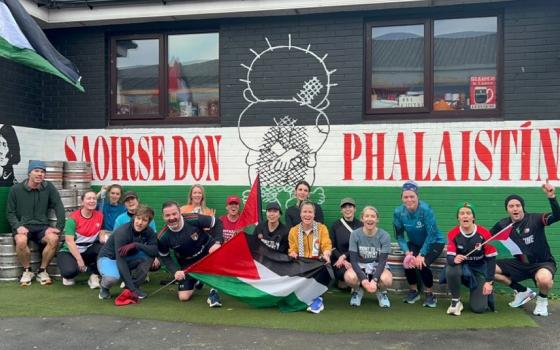 رياضيون أمام جدارية داعمة لفلسطين