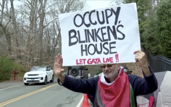 متضامن يرفع لافتة منددة بدعم بلينكن للاحتلال