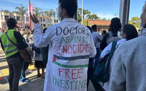 طبيب يرتدي قميصًا طبيًا بعبارات داعمة لفلسطين