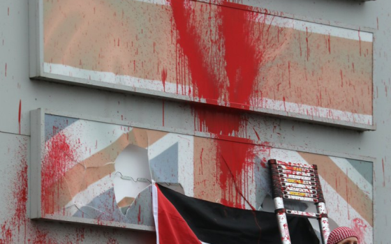 العلم الفلسطيني أمام جدار ملطخ بالطلاء الأحمر