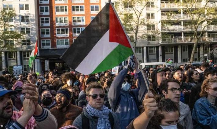 شخص يرفع علم فلسطين بمظاهرة