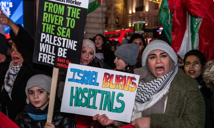 متظاهرة تهتف وتحمل لافتة تدين قصف الاحتلال للمستشفيات